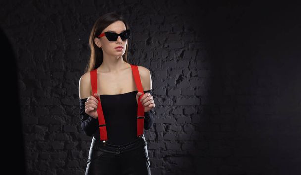 Stylish beautiful woman in fashionable sunglasses and red rises against the background of a stone wall. - Foto, Bild
