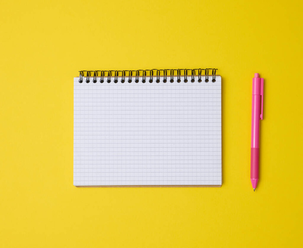 open notebook in a cage with white blank sheet and on a yellow background, top view - Foto, imagen