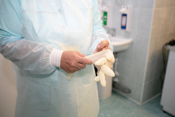 Ο γιατρός βάζει πλαστικά γάντια στα χέρια του.. - Φωτογραφία, εικόνα