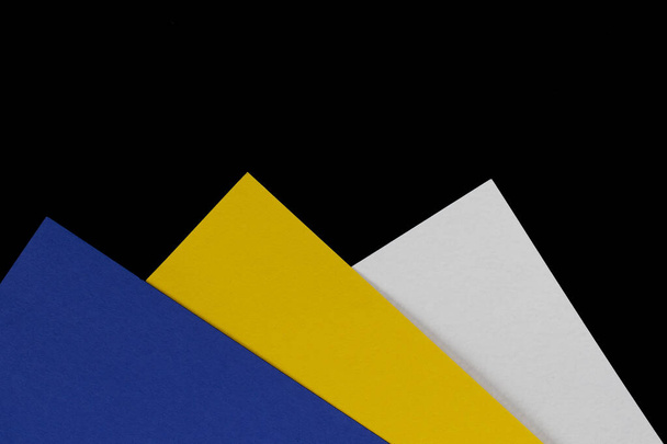 Multi-colored paper. Blue, yellow and white cardboard boxes on a black background. - Photo, Image