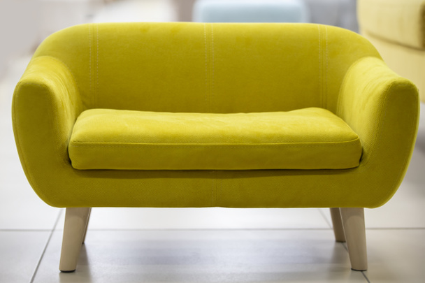 Kleines gelbes Sofa mit Holzbeinen. - Foto, Bild