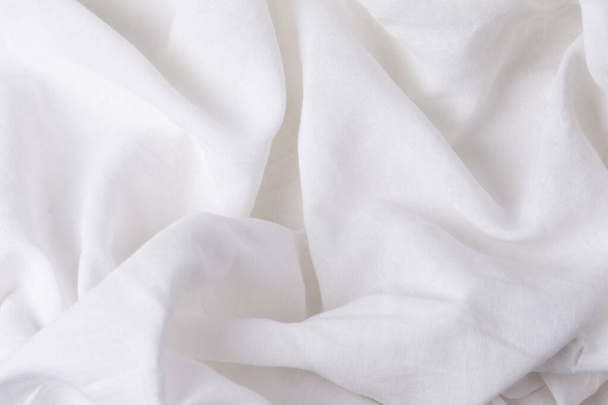 A fragment of crumpled white fabric as a background texture.Crumpled white linen or cotton fabric. - Photo, Image