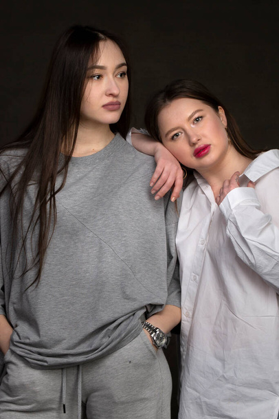 Two beautiful girls-friends on a dark background. - Foto, Imagem