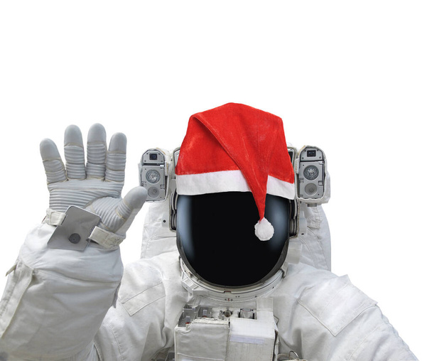 Astronauta en sombrero de santa roja levantar la mano como saludo. Aislado sobre fondo blanco. Elementos de esta imagen proporcionados por la NASA - Foto, Imagen