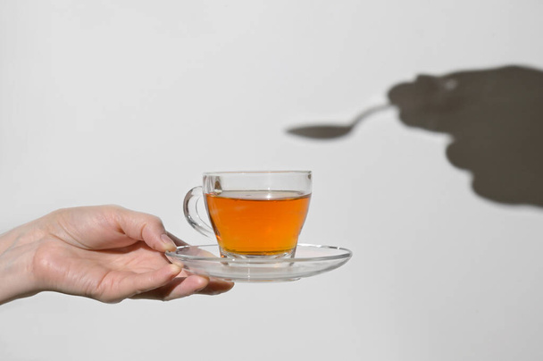 Conceptual Cup Of Tea and Shadow of Spoon and Hand - Photo, Image