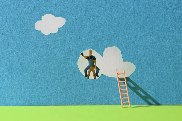 Conceptual worker on ladder repair or making clouds  - Photo, Image