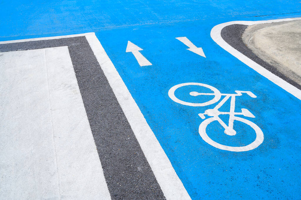 Blauwe fietspad op de weg met witte fiets pictogram en pijl. Lege fietspad voor fietsen - Foto, afbeelding