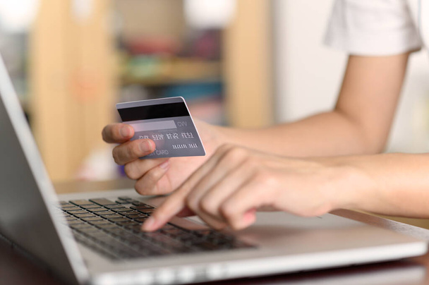 Κοντινό πλάνο χέρια γυναίκα κρατώντας πιστωτική κάρτα και χρησιμοποιώντας φορητό υπολογιστή αγορές σε απευθείας σύνδεση. e-commerce, internet banking, έλεγχος υπολοίπου, τραπεζικές υπηρεσίες, πληρωμή με πιστωτική κάρτα, πραγματοποίηση πληρωμών - Φωτογραφία, εικόνα