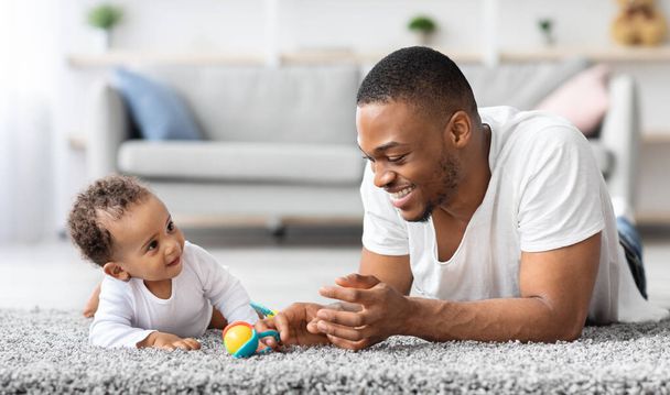 Father-infant bonding. Happy young black dad playing with baby son at home - Photo, Image
