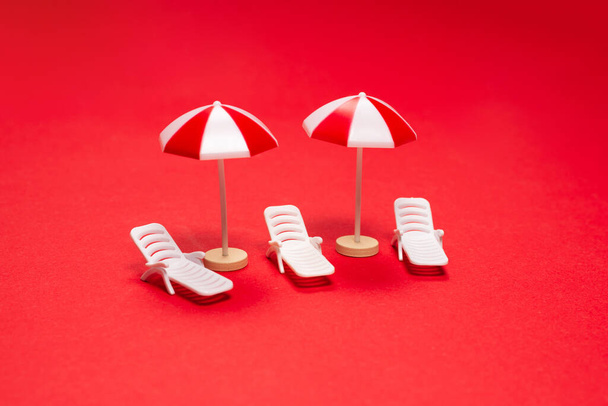 Two sun loungers and red umbrellas on a red background. Copy space. - Photo, Image