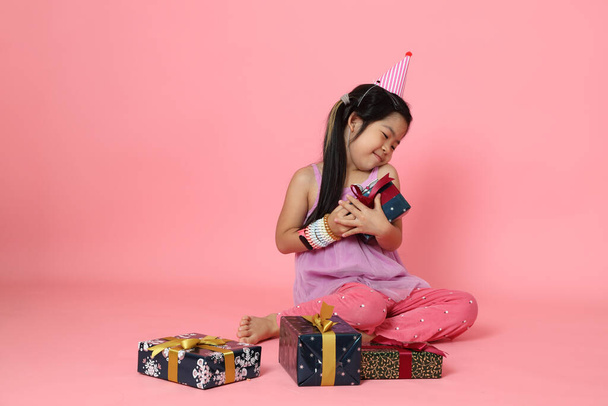 Młoda Azjatka siedzi z pudełkami na różowym tle. - Zdjęcie, obraz