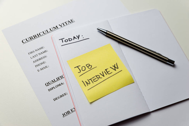 Curriculum vitae y cuaderno con billete amarillo y texto "entrevista de trabajo de hoy". Búsqueda de empleo y entrevistas de trabajo.  - Foto, imagen