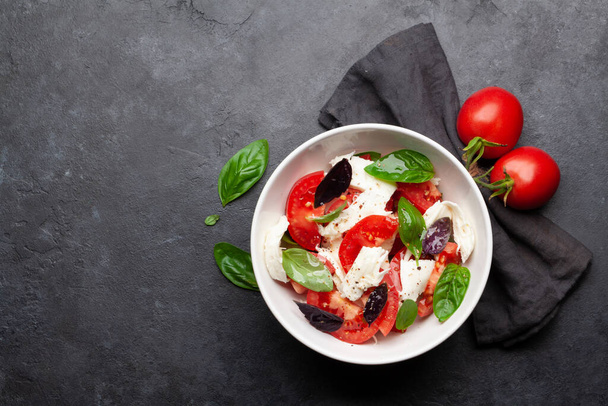 Caprese salad with fresh tomatoes, garden basil and mozzarella cheese. Top view flat lay with copy space - Фото, изображение