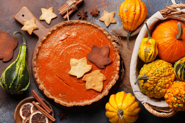 Homemade pumpkin pie on wooden board and various pumpkins. Top view flat lay - Photo, Image
