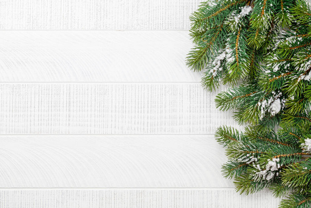 Vánoční přání šablona s jedlí větev přes bílé dřevěné pozadí. Horní pohled plochý ležel s kopírovacím prostorem - Fotografie, Obrázek