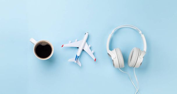 Concepto de viaje y vacaciones. Accesorios y artículos de viaje. Taza de café, juguete de avión y auriculares. Vista superior plano laico - Foto, Imagen