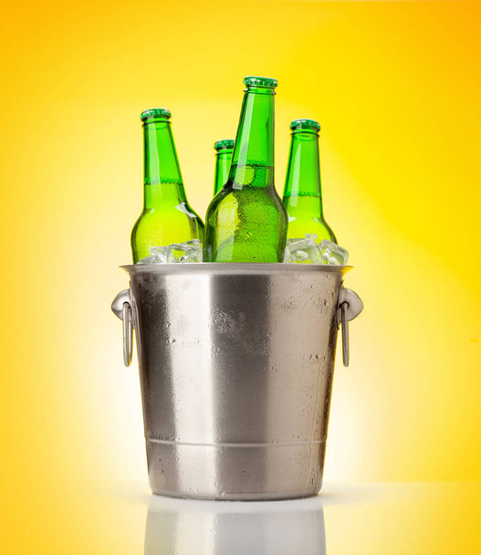 Láhev od piva v kbelíku s ledem. Přes žluté pozadí - Fotografie, Obrázek