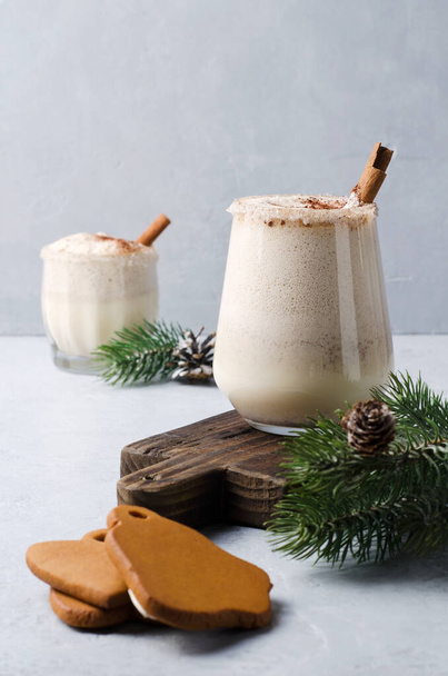 Eggnog with cinnamon and natural gingerbread on a gray background. Christmas drink egg punch with liquor - Fotoğraf, Görsel