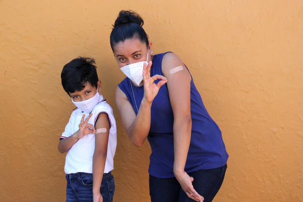 Madre e hijo latinos felices y emocionados muestran su brazo recién vacunado contra el Coronavirus en la nueva normalidad para la pandemia de Covid-19 - Foto, imagen