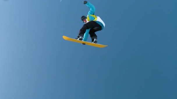 Movimiento lento: Joven snowboarder macho captura de aire grande y haciendo un truco de rotación. - Imágenes, Vídeo
