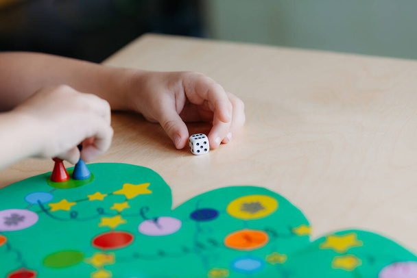 child hand rolls the dice and moves the chip across the Christmas playing field - 写真・画像