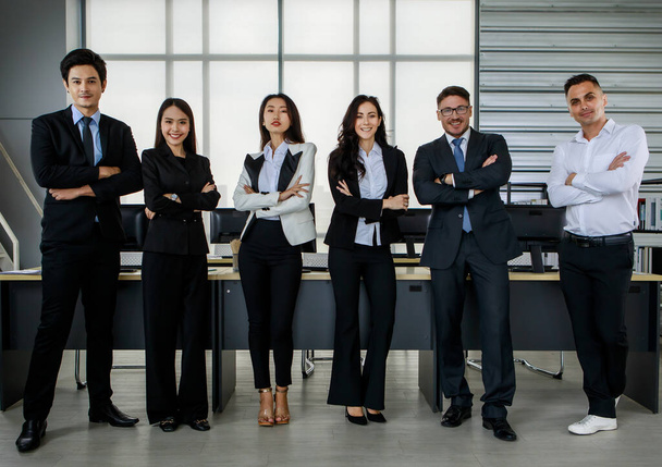 Multicultural diversity Asian Caucasian businessman and businesswoman colleague team in formal business suit standing side by side crossed arms together in front working desk in company office. - Photo, Image