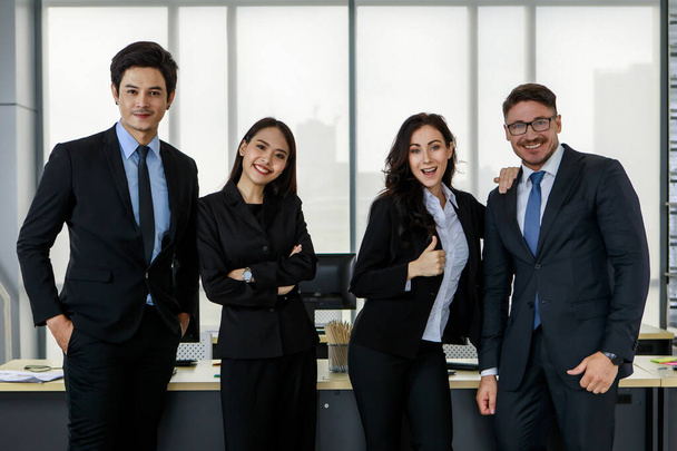 Multicultural diversity Asian Caucasian businessman and businesswoman colleague team in formal business suit standing together in front working desk in company office. - Photo, Image