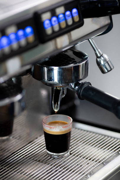 Крупним планом фото приготування кави з машиною в кафе. Професійна сучасна кавоварка з еспресо вливає гарячий напій у чашку. Концепт кави в кафе
 - Фото, зображення