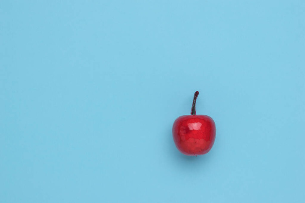 Roter Apfel in Sirup auf blauem Hintergrund. Minimalismus. Das Konzept eines winterlichen süßen Apfelgerichts. Flache Lage. - Foto, Bild