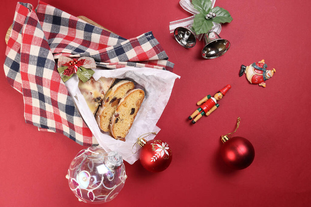 Christmas xmas decoration ornament bell gift checked fabric cloth wrap sliced stollen fruit cake food pine fruit on red background - Foto, Imagem