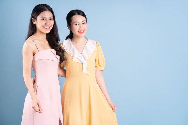 Zwei junge asiatische Frauen tragen Kleid auf blauem Hintergrund - Foto, Bild