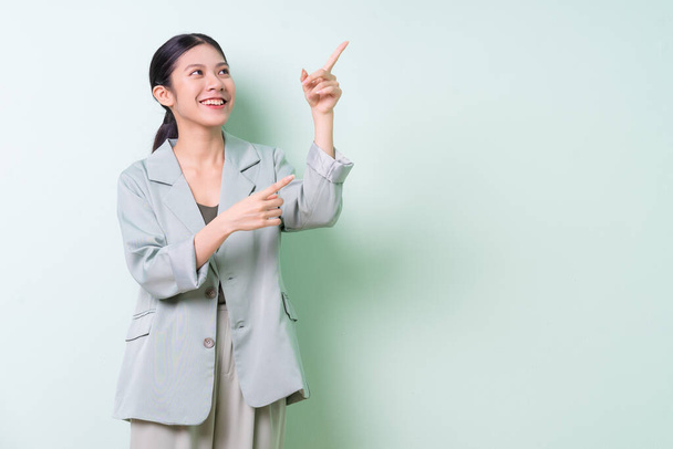 jong aziatisch zakenvrouw dragen groen pak op groen achtergrond - Foto, afbeelding