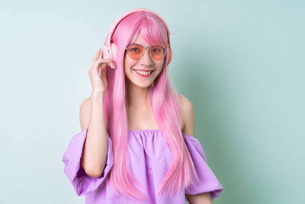 Молода азіатка з рожевим волоссям на зеленому тлі. - Фото, зображення