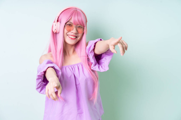 Молодая азиатка с розовыми волосами позирует на зеленом фоне - Фото, изображение
