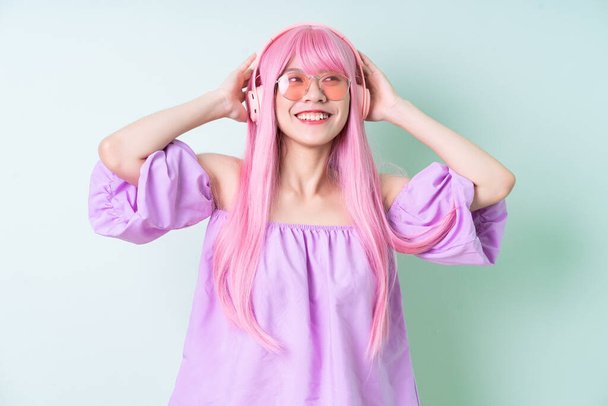 Jeune femme asiatique aux cheveux roses posant sur fond vert - Photo, image