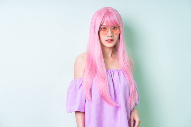 Junge Asiatin mit rosa Haaren posiert auf grünem Hintergrund - Foto, Bild