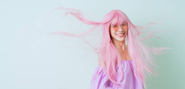 Молода азіатка з рожевим волоссям на зеленому тлі. - Фото, зображення