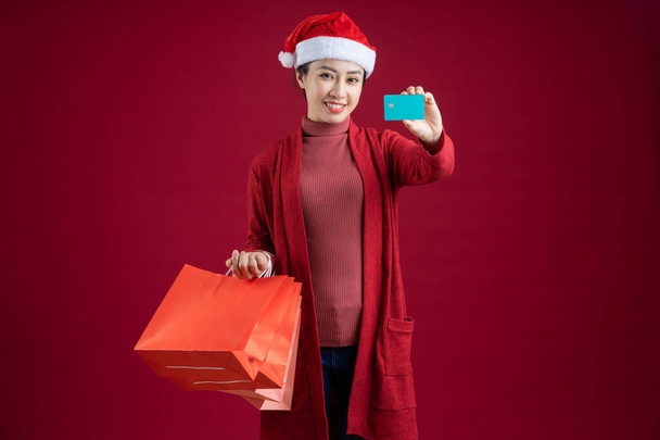 Mujer asiática joven con sombrero de Navidad sobre fondo rojo - Foto, Imagen