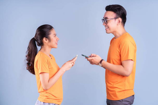 Joven pareja asiática con camiseta naranja sobre fondo azul - Foto, Imagen