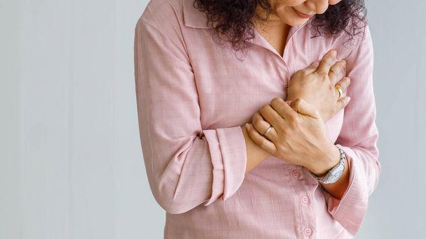 Ani kalp krizi geçiren yetişkin bir kadın ve çarpık suratlı el ele tutuşan bir göğüs kullanıyor. Acil sağlık hizmeti kavramı ve konjestif yetmezlikten ya da kardiyopulmoner resüsitasyondan, kalp sorunundan etkilenme. - Fotoğraf, Görsel