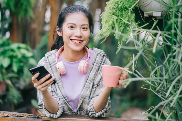 Młoda Azjatka za pomocą smartfona w ogrodzie - Zdjęcie, obraz
