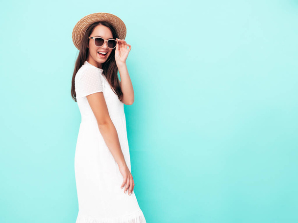 Young beautiful smiling female in trendy summer clothes. Sexy carefree woman posing near blue wall in studio. Positive brunette model having fun. Cheerful and happy. In hat - Φωτογραφία, εικόνα