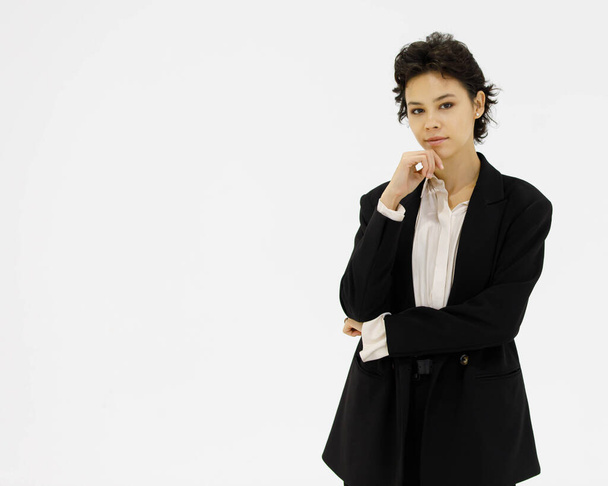 Confident well dressed female entrepreneur in black formal suit standing with self confident on white background in studio and looking at camera. - Foto, Imagem