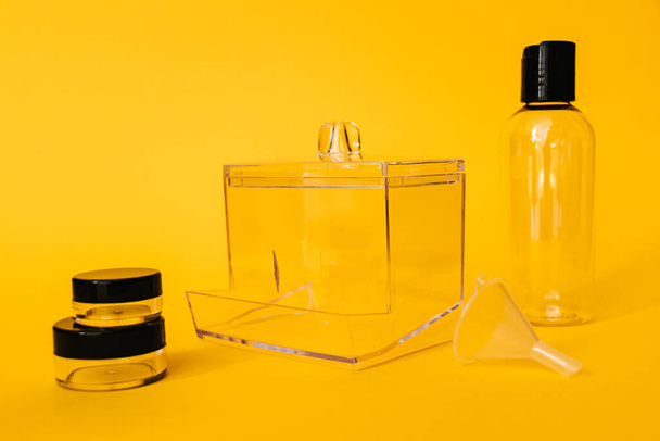 黄色の背景に化粧品のための黒い蓋付き透明プラスチック容器の旅行セット - 写真・画像