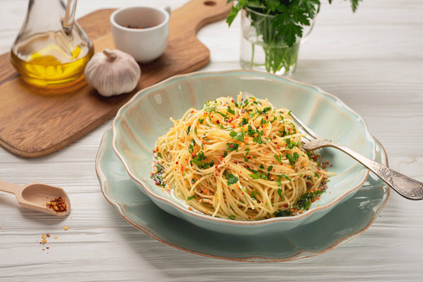 Assiette de spaghettis fraîchement cuits AGLIO E OLIO et ingrédients sur table en bois - Photo, image