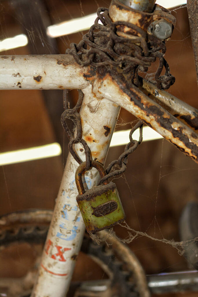 A vertical shot of an old chain with a lock around a rusty railing - Фото, зображення