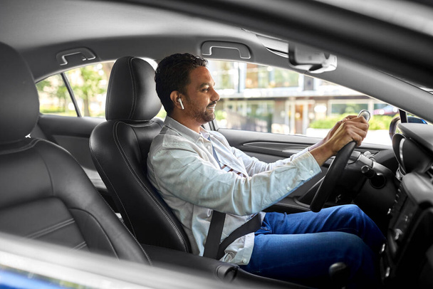 man or driver with wireless earphones driving car - Foto, Imagen