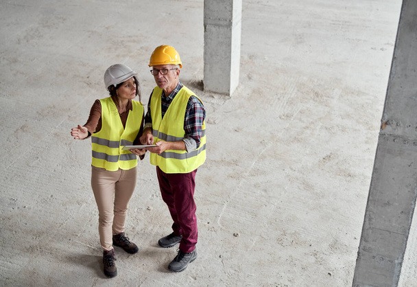 High angle view  video of male and female caucasian engineers discussing and pointing on the construction site - Photo, Image