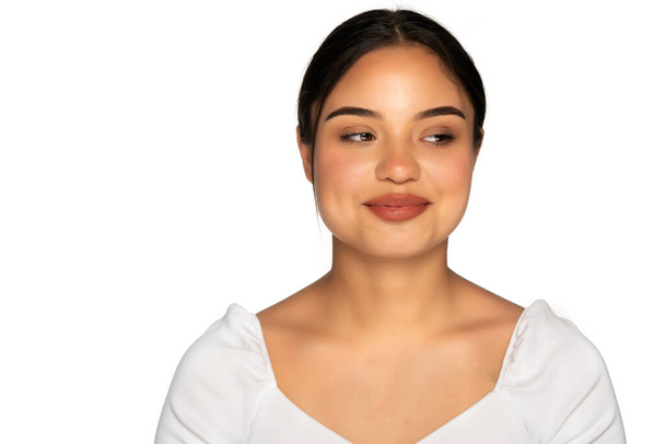 a young smiling woman without makeup looks away at a white background - Photo, Image