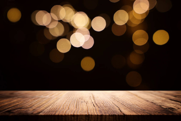 wooden table in front of glitter black and gold bokeh lights. For product presentation - Foto, Imagem